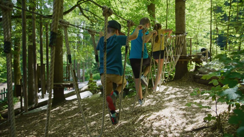 Gemeinsam durch den Waldseilgarten im Freizeitpark Ruhpolding klettern. 